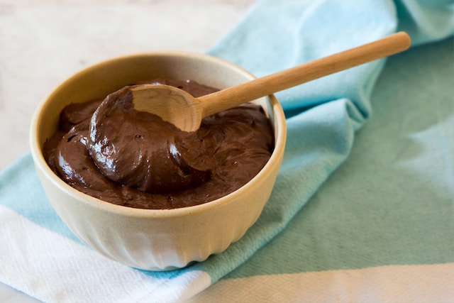 A small bowl of chocolate pudding with a wooden spoon
