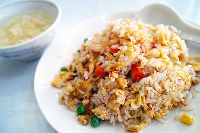 A plate of fried rice with a small bowl of soup on the side