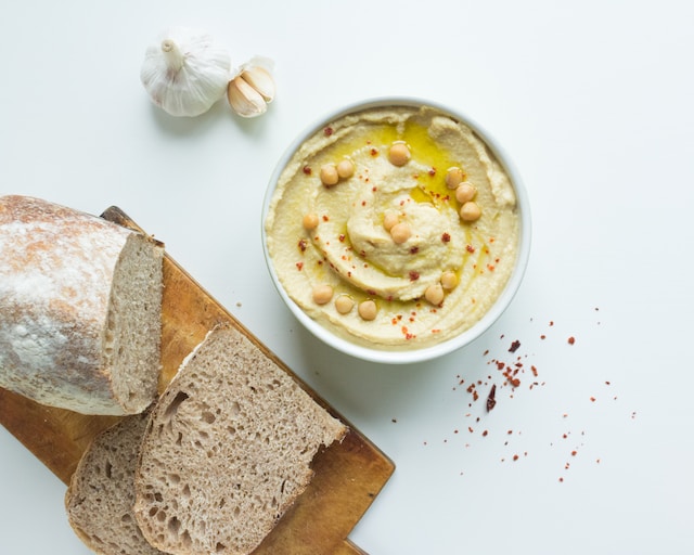 A bowl of hummus with bread on the side