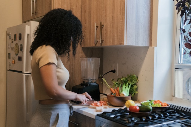 A woman cutting vegetables on a worktop.