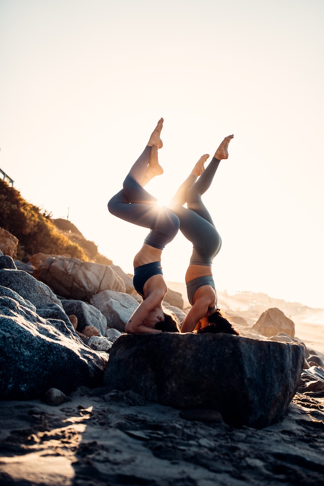 Two women doing yoga together on top of a flat rock