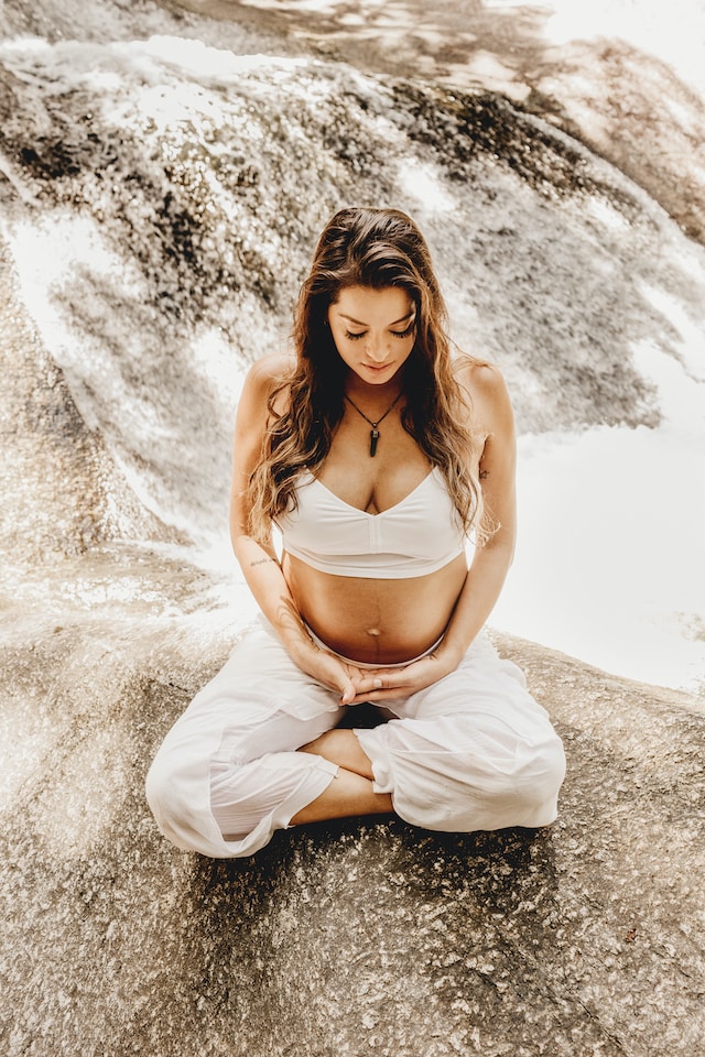 A pregnant woman meditating outdoors
