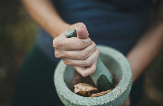 Person grinding herbs on a mortar and pestle