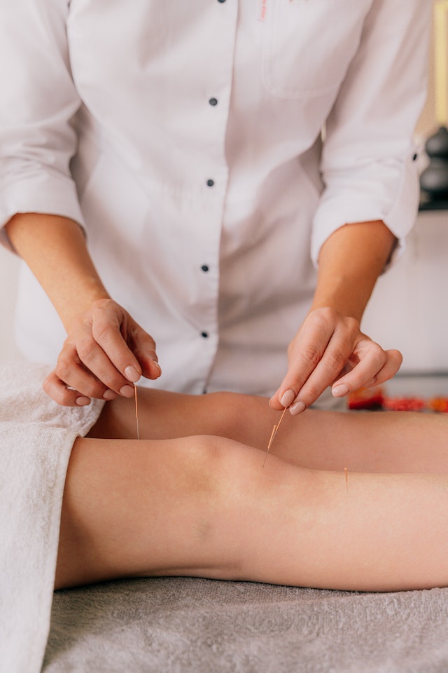 person inserting tiny needles into a patient's knees