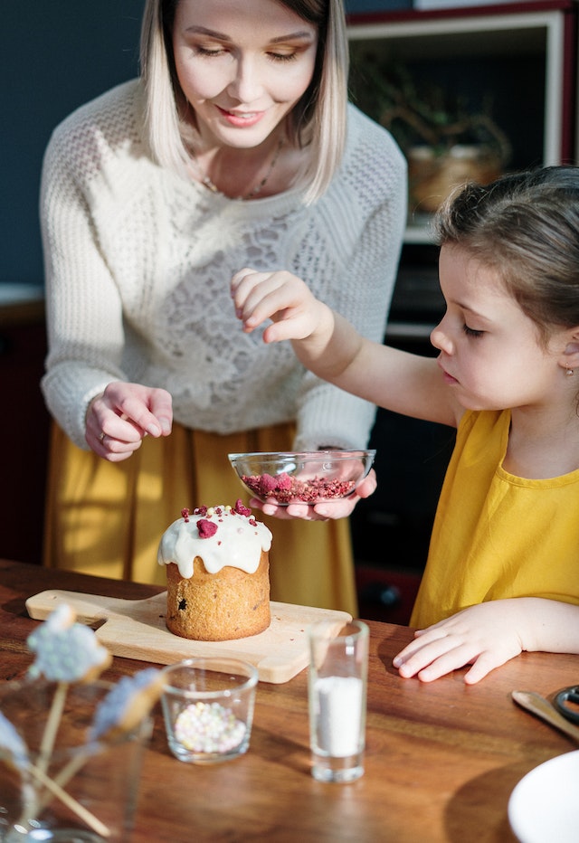 Mother and daughter decorating a tiny cake 