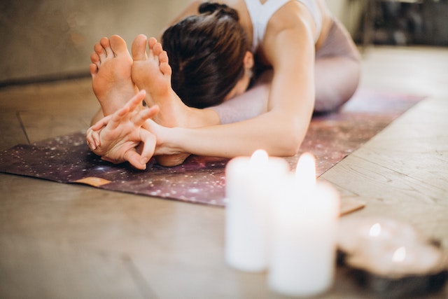 Woman doing a yoga stretch with lighted scented candles on the side