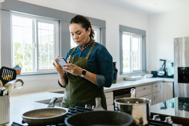 Woman checks her phone while cooking in the kitchen