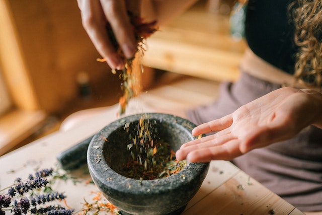 Person mixing herbs and spices on a mortar and pestle