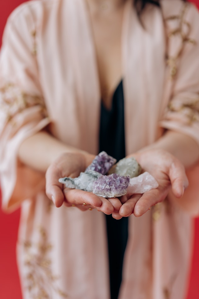 person with crystals and precious stones on their hands