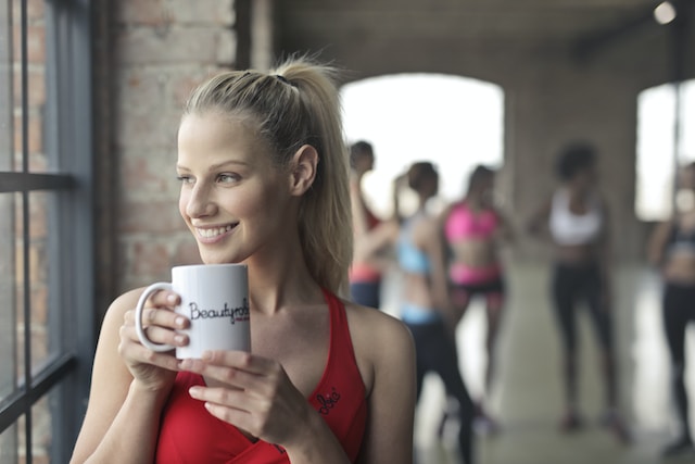 Woman holding a white ceramic mug while taking a break from a workout