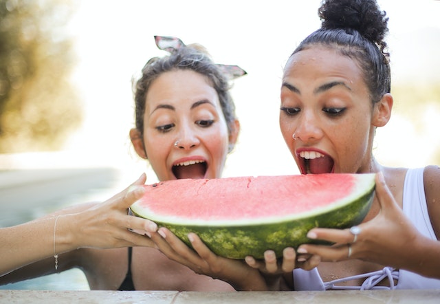 Two women about to take a bite on a slice of watermelon 