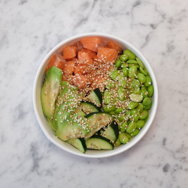 Salad bowl with tuna avocado, zucchini, and green beans topped with sesame seeds
